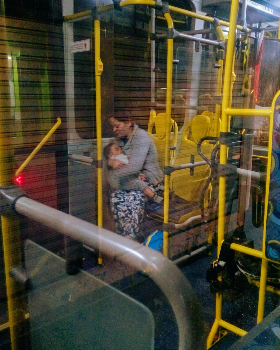 Uma mulher sentada em um ônibus segurando um bebê nos braços.